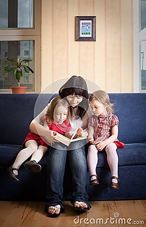 Mother reading a book to her little daughters