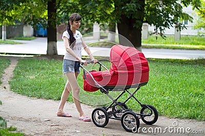 Mother with a red baby carriage on walk