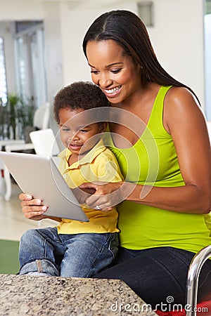 Mother And Son Using Digital Tablet In Kitchen Together