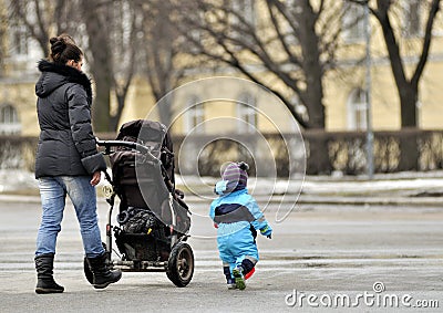 Mother with stroller walking near little son