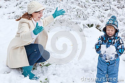 Mother and toddler boy having fun with snow