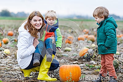 Mother and two little sons having fun on pumpkin patch.