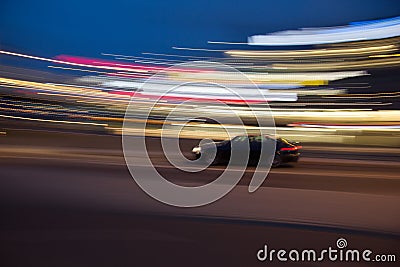 Motion blur of a car in a curve with city light trails