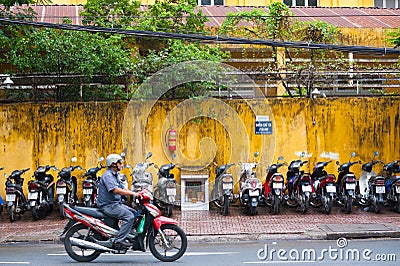 Motorcyclist moves by motorcycle parking lot, Saigon