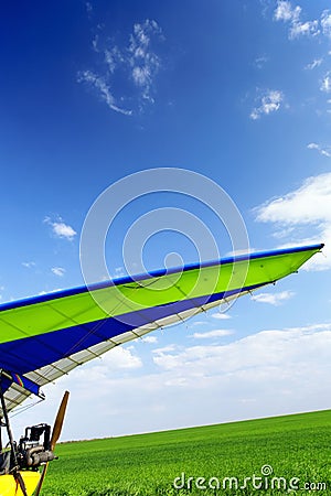 Motorized hang glider over green grass