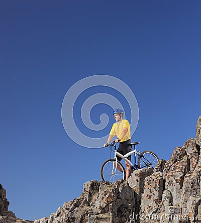 Mountain biker standing on a rocky cliff