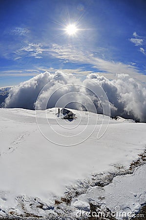 Mountain chalet in winter landscape above the clouds