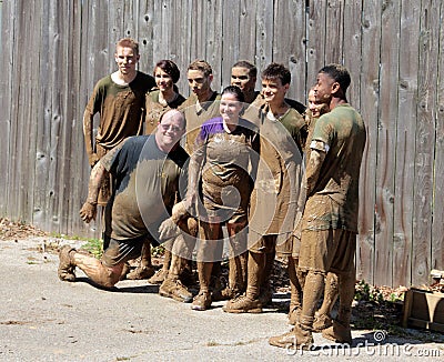 Muddy Group of People Poses for Picture after completing a Mud Run