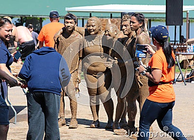 Muddy Group of People Poses for Picture after completing a Mud Run