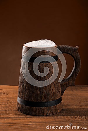 Mug beer with a cap of foam on a dark background