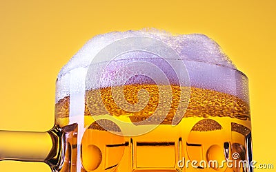 Mug fresh beer with cap of foam over yellow background