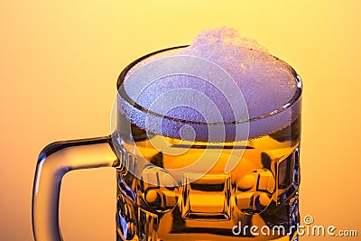 Mug fresh beer with cap of foam over yellow background