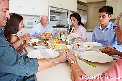 Multi-Generation Family Saying Prayer Before Eating Meal