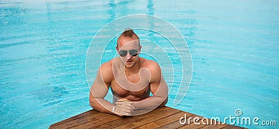 Muscular man posing in the swimming pool