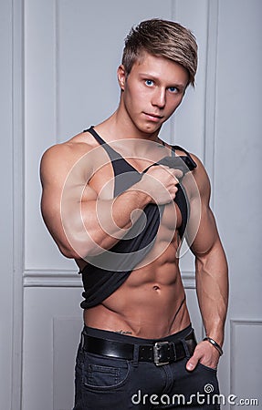 Muscular young sexy man takes off black t-shirt