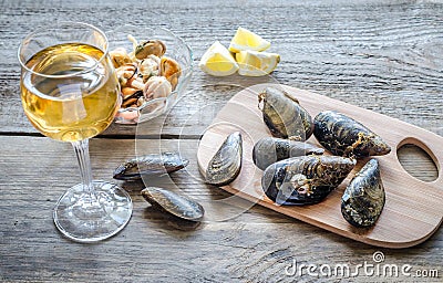 Mussels with a glass of white wine on the wooden table