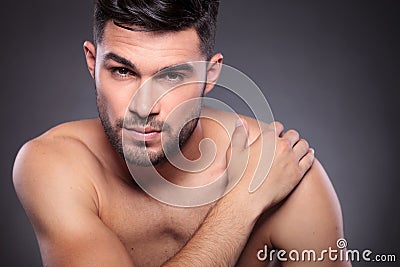 Naked young man holds hand on shoulder