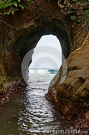 Natural tunnel in the rock dug by sea waves