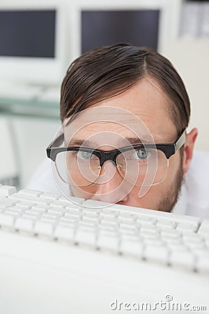 Nerdy businessman hiding behind keyboard