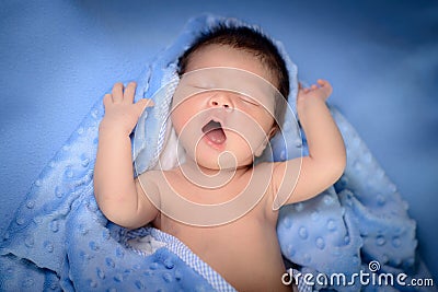 Newborn baby boy plays on blue blanket