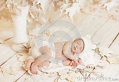 Newborn baby sleeping on leaves over white wooden