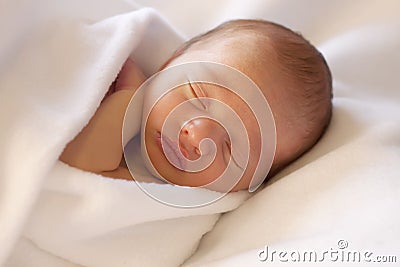 Newborn baby sleeping wrapped in white blanket