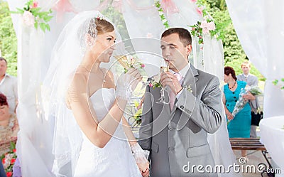 Newly married couple drinking champagne in alcove