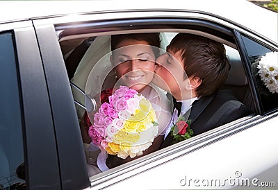Newlywed couple kissing in wedding car