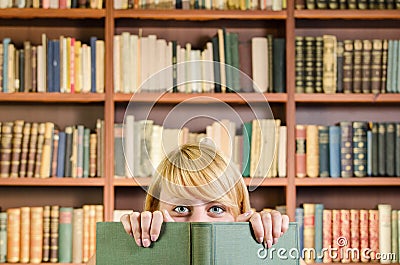 Nice blonde girl hiding behind a book