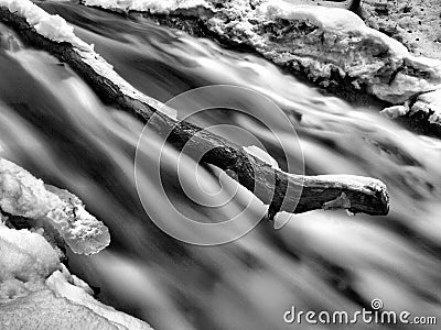 Night winter view to frozen cascade of waterfall, icy twigs and icy boulders in frozen foam of rapid stream. Reflections of light