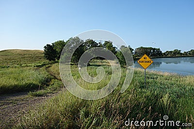 A no road maintenance sign beside a lake