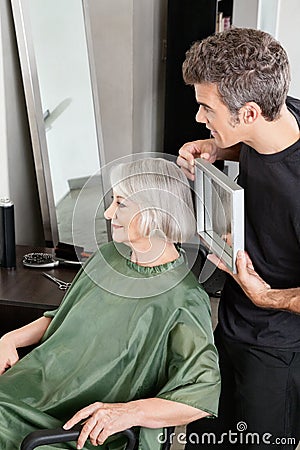 拿着在资深妇女后的<em>美发师镜子</em> 免版税库存照