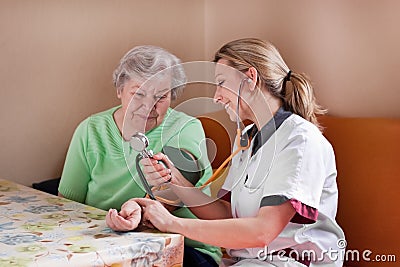 Nurse measures blood pressure of an elderly woman