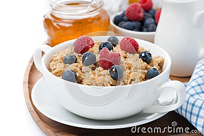 Oat porridge with berries and honey, close-up, isolated
