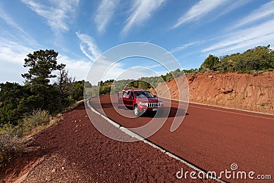 Off road car on red tarmac in high mountains