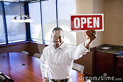 Office worker holding open sign in empty boardroom