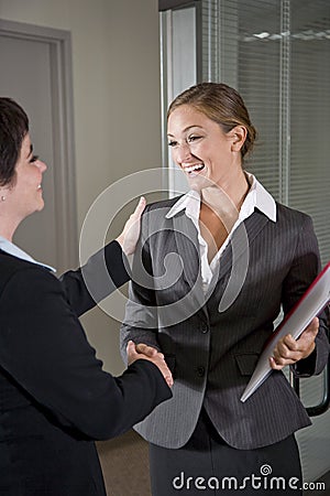 Office workers shaking hands at door of boardroom