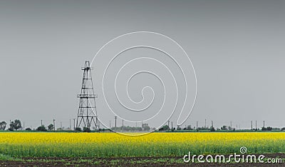 Oil and gas well rig, outlined rural canola field