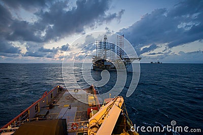 Oil rig platform towed by an offshore vessel during sunset