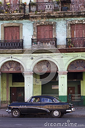 Old black Cuban car and dilapidated building