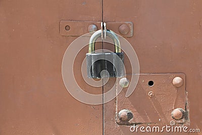 Old black padlock on a red metal garage door