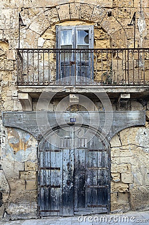 Old building front showing garage and window above balcony