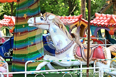 Old carousel in a holiday park with beautiful white horse