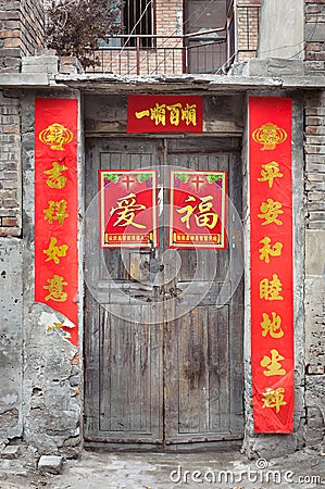 Old Chinese door with peeling fortune posters