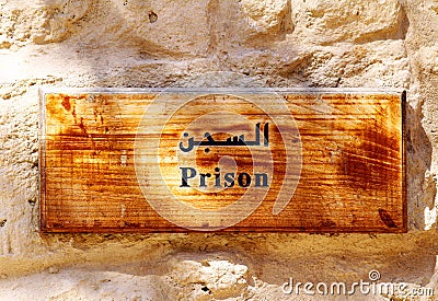 An old-fashioned wooden prison sign hanging on a wall.