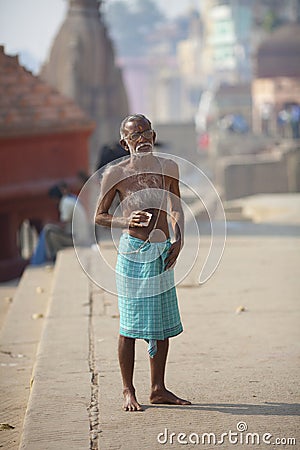 Old hairy indian man drinking tea at river Ganges,