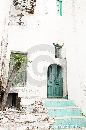 Old house facade with green wooden door looking like a ruin.