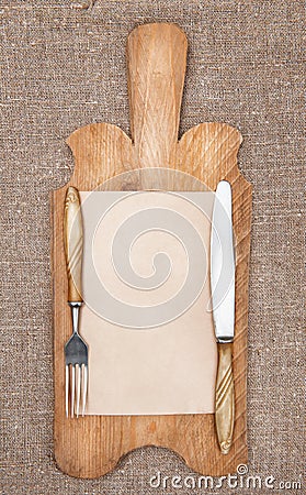Old kitchen board with aged paper, fork and knife