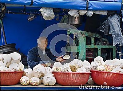 Old korean man making corn flat bread