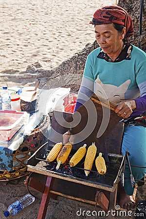 Old lady preparing grilled corn